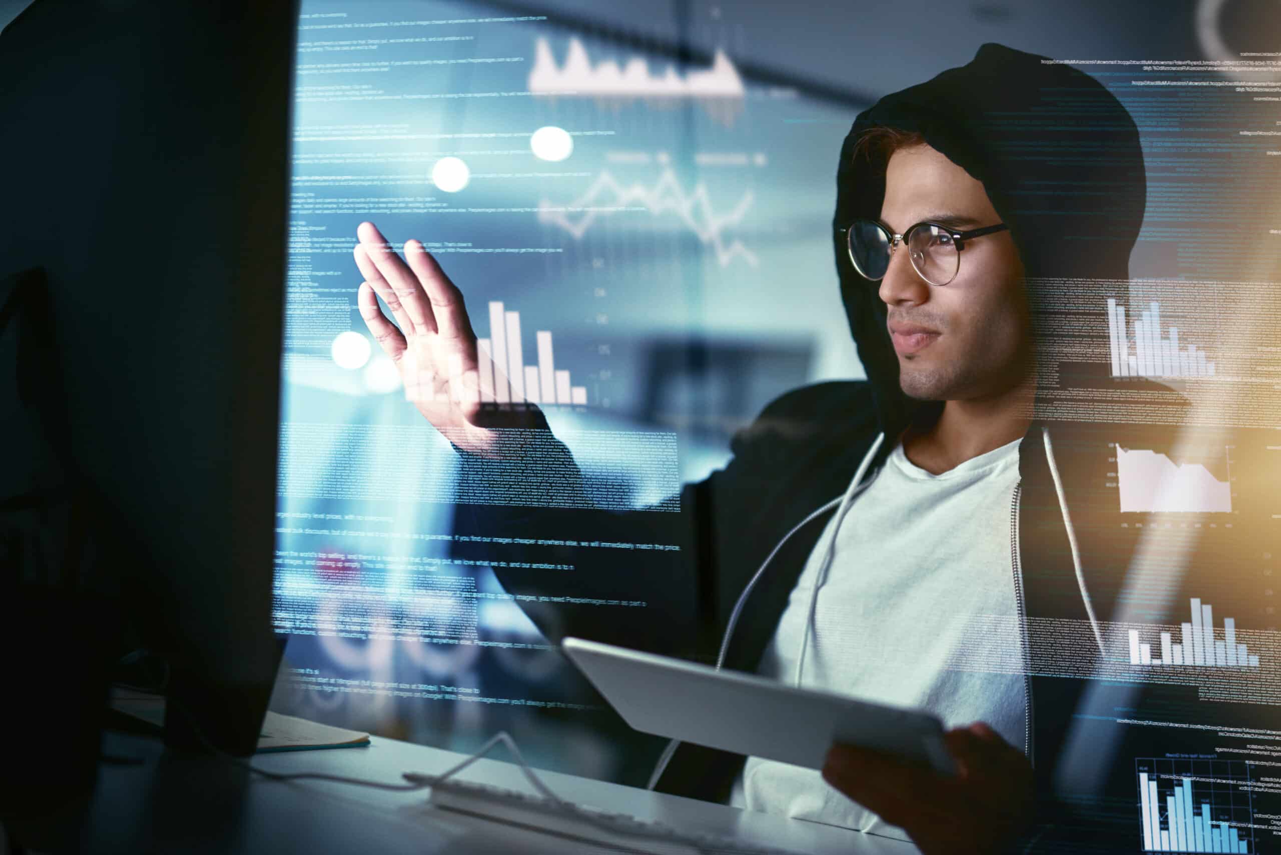 Hackers are the masters of stealth. Shot of a young hacker cracking a computer code in the dark